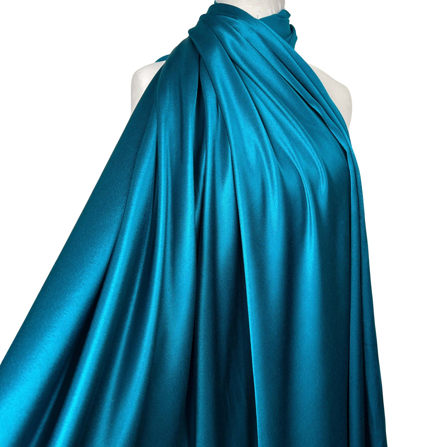 A teal blue satin fabric draped elegantly over a white mannequin torso against a solid white background.